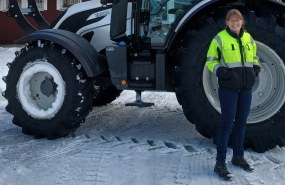 Nainen seisoo traktorin edessä talvella