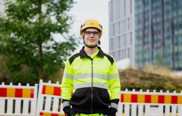 Kuva Jaakko Heinosta, hän seisoo työmaa-alueella työvaateet päällä.